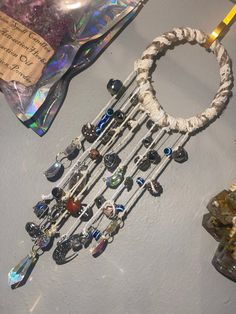 an assortment of beads and necklaces hanging from a string on a table next to a bag