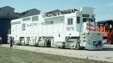 an old train car is parked on the side of the road with people standing around it