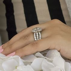 a woman's hand with two diamond rings on top of her wedding dress bouquet