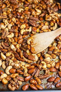 a wooden spoon is stirring nuts in a pan