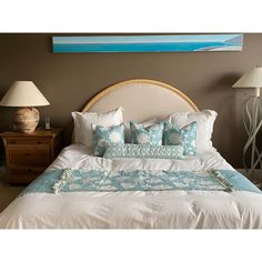 a bed with white and blue pillows on top of it next to two nightstands