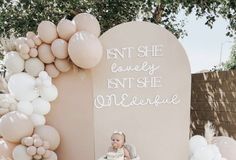 a baby sitting in a high chair next to balloons and a sign that says, snuggley isn't she somewhere