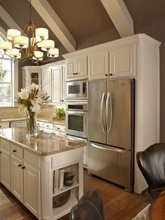 a kitchen with white cabinets and stainless steel appliances, including a center island in the middle