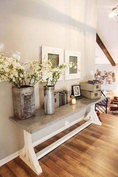 some flowers are sitting on a shelf in the middle of a room with wood floors