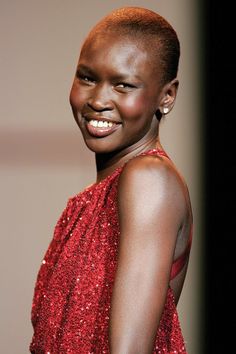 a woman in a red dress smiles at the camera while standing on a catwalk