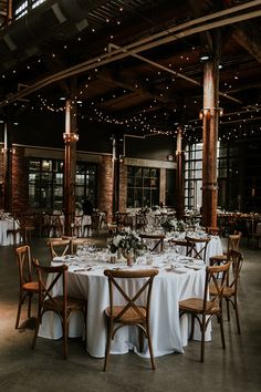 the tables are set with white linens and wooden chairs for an elegant wedding reception