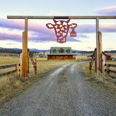 an open gate leading to a house with a cow head cut out on it's side