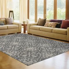 a living room with two couches and a rug on the floor in front of windows