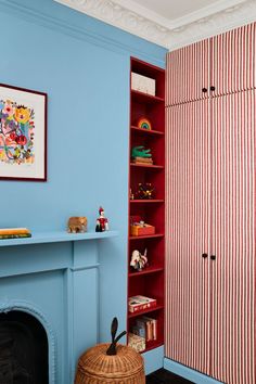 a living room with blue walls and a red bookcase next to a fire place