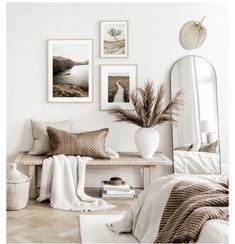 a white room with pictures on the wall and a bench in front of some pillows