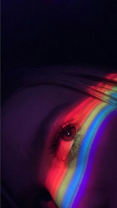 a woman's face with multicolored light coming out of her iris eye