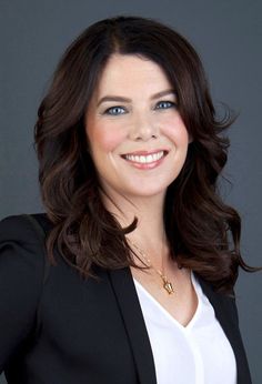 a smiling woman in a black blazer and white shirt