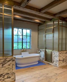 a bathroom with marble walls and flooring in the shower area, along with a large bathtub