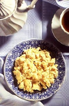 scrambled eggs on a blue and white plate next to a cup of coffee