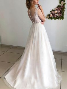 a woman in a wedding dress standing next to a wreath