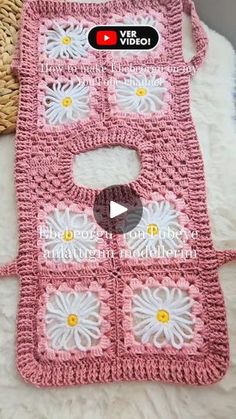 a pink crocheted bag with white flowers on it