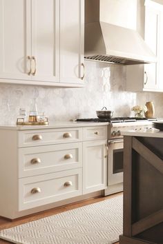 a kitchen with white cabinets and an oven in the center, along with a rug on the floor