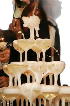 a woman pouring champagne into wine glasses in front of a large display of ice sculptures