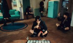 a group of young men sitting on the floor in front of a table with an electronic keyboard