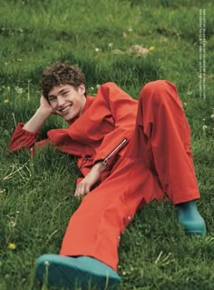 a young man laying in the grass wearing an orange jumpsuit