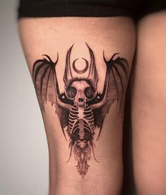 a woman's thigh with a skeleton and bat tattoo on it