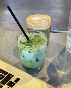 two drinks sitting next to each other on top of a table in front of a laptop