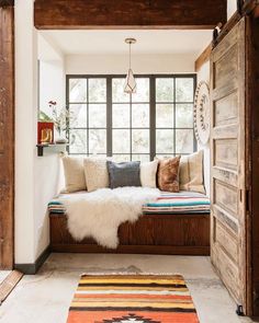 an entryway with a bench, rug and window seat in it's center