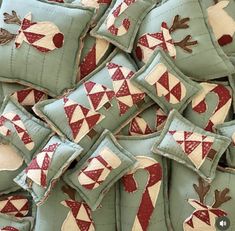 a pile of green pillows with red and white appliqued designs on them