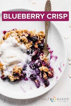 a white plate topped with blueberry cobbler and ice cream next to a spoon