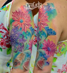 the back of a woman's arm with colorful flowers and feathers painted on it