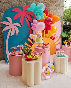 there are many balloons and desserts on the table in front of this wall that is decorated with palm trees