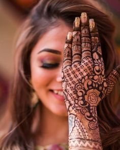 a woman holding her hands up to her face with henna tattoos on it's palms