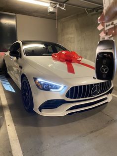 a white car with a red bow tied around it's hood and door handle