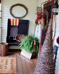 a porch decorated for the fourth of july with wreaths and potted plants on it