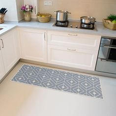 a kitchen area with white cabinets and blue rugs on the floor next to an oven