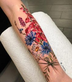 a woman's arm with flowers on it and a bird sitting on the flower