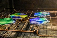 four colorful glass coasters sitting on top of an oven rack