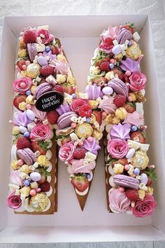 the letter m is made up of cakes and flowers on top of each other in a box