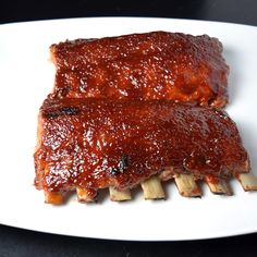 two ribs covered in bbq sauce on a white plate