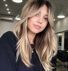 a woman with long blonde hair standing in front of a barbershop and looking at the camera