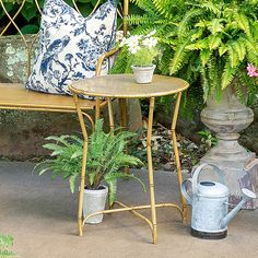 a table and chair sitting next to each other in front of some plants on the ground