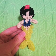 a hand holding a small toy on top of a green bed cover covered in crochet