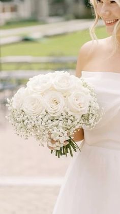 a woman holding a bouquet of white flowers