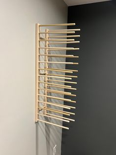 a wooden rack with clothes hanging from it's sides on the wall next to a gray wall