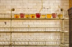 several glasses are lined up on shelves in a room with white brick walls and flooring