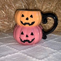 two pumpkin mugs are stacked on top of each other in front of some hay