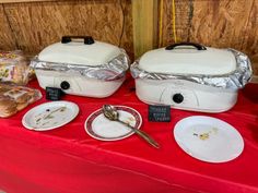 two white crockpots sitting on top of a red table