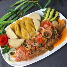 a white plate topped with fish and veggies on top of a black table