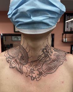 a man with a dragon tattoo on his neck and behind him is a blue surgical mask