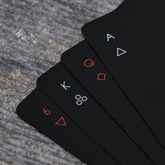 four black playing cards sitting on top of a gray cloth covered table with numbers and symbols